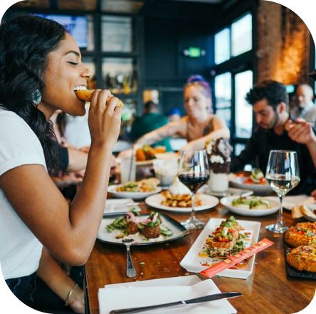Frau genießt Essen in geselliger Runde dank angenehmer Raumbeduftung für Restaurants